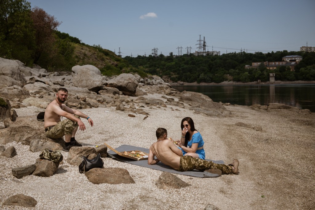 Soldați ucraineni mâncând pizza lângă ceea ce a mai rămas din lacul de acumulare la o lună de la distrugerea barajului Nova Kahovka / FOTO Andre Luis Alves / AFP / Profimedia